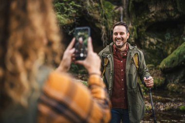 Eşi, sırt çantalı Whit yürüyüş sopalarını ormanda ön mağarada çekerken fotoğrafını çekmiş.