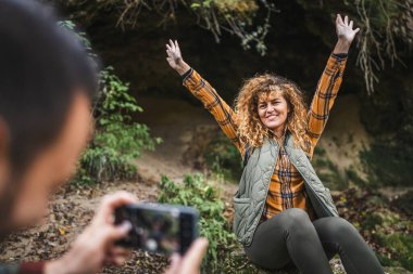 Koca, eşinin ön mağarada sırt çantasının ve ormandaki şelalenin fotoğrafını çeker.