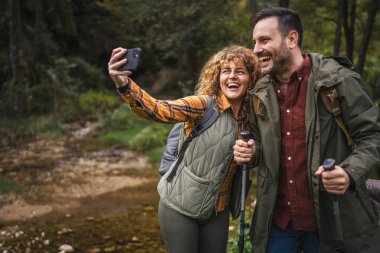 Karı koca yürüyüşçüleri sırt çantasıyla gezerler. Ormanda yürüyüş yaparken kendi portresini ya da video görüntülerini çekerler.