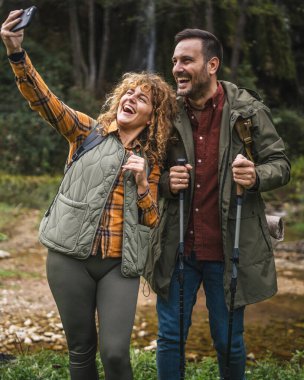 Karı koca yürüyüşçüleri sırt çantasıyla gezerler. Ormanda yürüyüş yaparken kendi portresini ya da video görüntülerini çekerler.