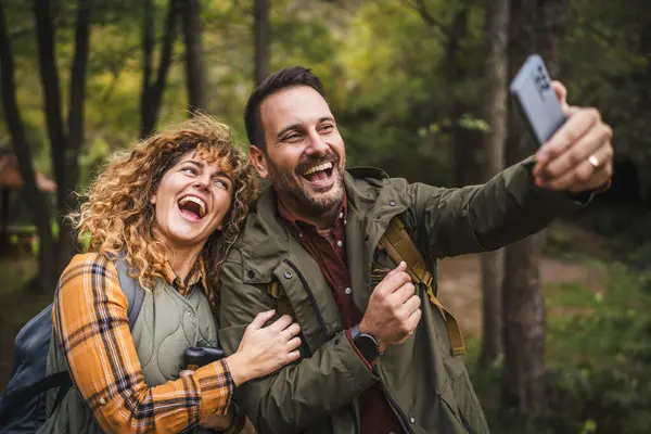 Karı koca yürüyüşçüleri sırt çantasıyla gezerler. Ormanda yürüyüş yaparken kendi portresini ya da video görüntülerini çekerler.