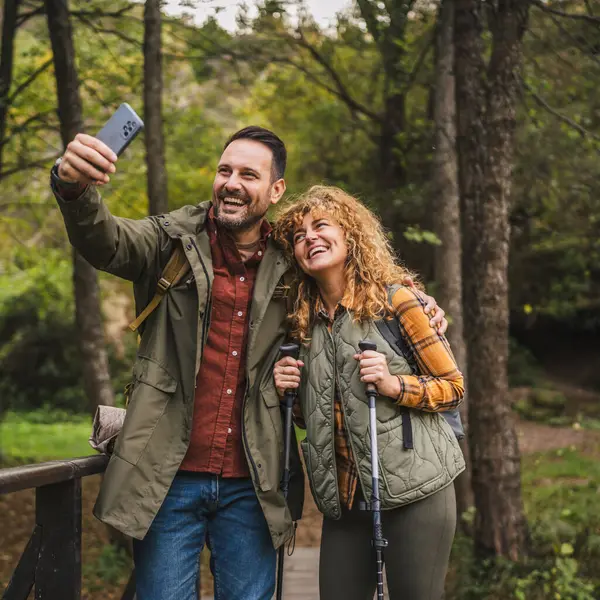 Karı koca yürüyüşçüleri sırt çantasıyla gezerler. Ormanda yürüyüş yaparken kendi portresini ya da video görüntülerini çekerler.