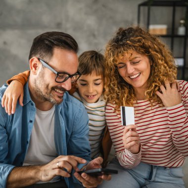 Anne, baba ve oğul evde kredi kartıyla internet üzerinden alışveriş yapıyorlar.