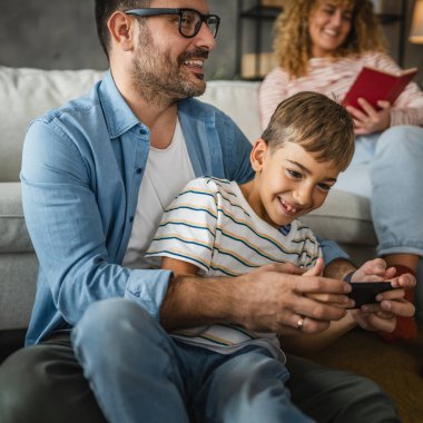 Baba ve oğul ve anne arkada cep telefonuyla oyun oynuyorlar.