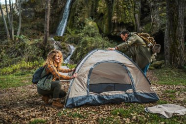 Karı koca, şelale ve mağaranın önünde manzaralı bir orman bölgesinde küçük bir çadır kurmuşlar. İkisi de heyecanlı ve kamp macerasına hazırlanıyorlar.