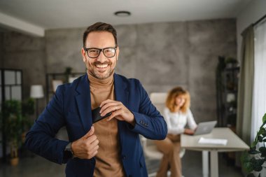 Yakışıklı iş adamının portresi telefonu takım elbisesinin cebine koyar.