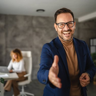 İş adamı portresi gülümse ve ofise hoş geldin demek için elini uzat.