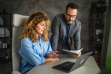 İki meslektaş dizüstü bilgisayarda ve zarftan alınan bilgilerle birlikte çalışıyor