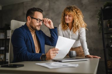 İki meslektaş birlikte çalışıyor ve ofiste kontratı gözden geçiriyorlar.