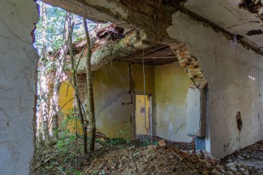 Eski ve yıpranmış bir binanın içindeki harabeler, çökmüş bir duvarla dışını ortaya çıkarıyor. Yapı, zamanın tahribatı yüzünden çökmeye başladı.