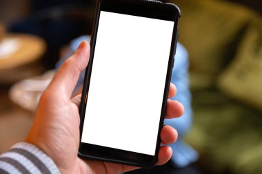 Metin veya özel içerik için beyaz ekranı olan bir adamın elindeki cep telefonunun yakın plan görüntüsü. Bulanık arkaplan