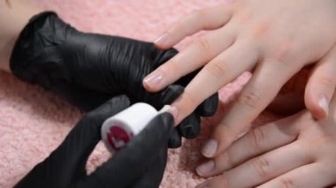 Güzellik uzmanının, manikür konsepti olan güzellik salonundaki müşterinin tırnaklarına jöle sürmesi.