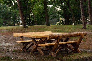 Yağmur sırasında parktaki ahşap retro bank ve masa. Yağmurlu bir sonbahar gününde çamurun içinde bankta