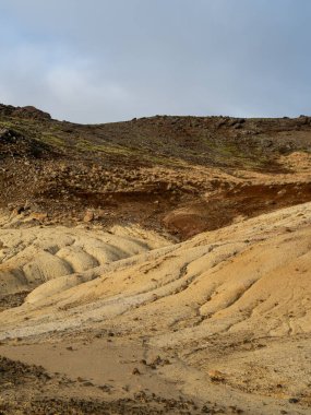 İzlanda 'nın Krisuvik bölgesindeki kaynayan bir jeotermal bacadan buhar yükseliyor. Zengin toprak tonları ve engebeli dokular adaların volkanik güçlerinin iş başında olduğunu gösteriyor
