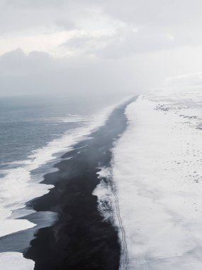 Ingjaldshlskirkja Kilisesi İzlanda 'da dramatik fırtına bulutlarının altında karlı bir tepede. Snfellsnes Yarımadası 'ndaki kırmızı çatılı şapel ve karanlık kış gökyüzü arasında çarpıcı bir tezat