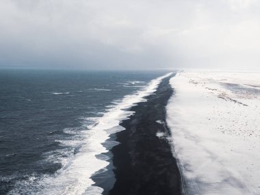 Ingjaldshlskirkja Kilisesi İzlanda 'da dramatik fırtına bulutlarının altında karlı bir tepede. Snfellsnes Yarımadası 'ndaki kırmızı çatılı şapel ve karanlık kış gökyüzü arasında çarpıcı bir tezat