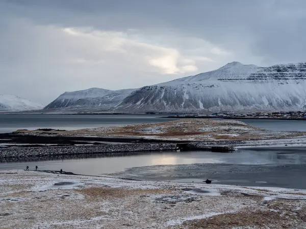 Ingjaldshlskirkja Kilisesi İzlanda 'da dramatik fırtına bulutlarının altında karlı bir tepede. Snfellsnes Yarımadası 'ndaki kırmızı çatılı şapel ve karanlık kış gökyüzü arasında çarpıcı bir tezat