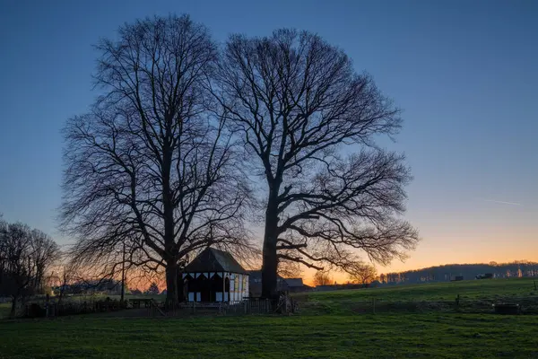 Gün doğumunda ağaçların altındaki küçük şapelin panoramik görüntüsü, Bergisch Gladbach, Almanya