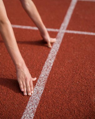 Stadyumun başlangıç çizgisinde bir atlet duruyor..