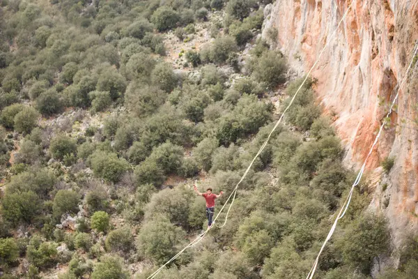 stock image A man walks on a tightrope over an abyss.