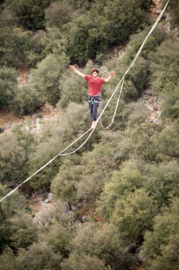 Bir adam uçurumun üzerinde ip üzerinde yürür..