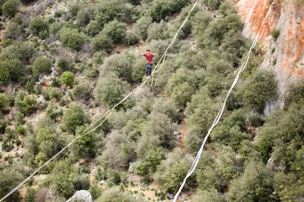 stock image A man walks on a tightrope over an abyss.