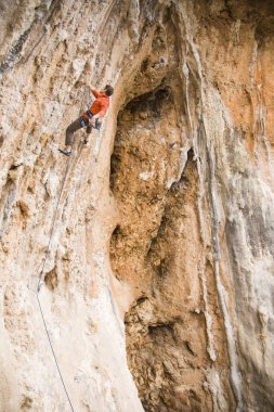Bir kaya tırmanışçısı zor bir yol boyunca bir dağın tepesine tırmanır..