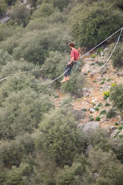 stock image A man walks on a tightrope over an abyss.