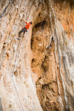 Bir kaya tırmanışçısı zor bir yol boyunca tepeye tırmanır..