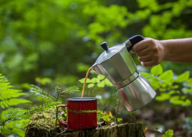 Kahve demliği ve metal bardak dağ nehrinin arka planına karşı büyük taşın üzerinde. Kahve demliği taştan tabakta, bulanık arka plan..
