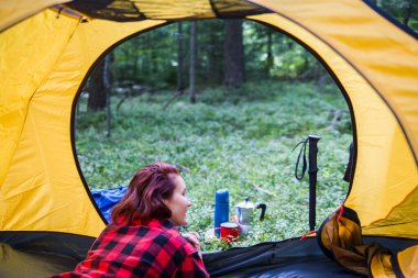 Ormanın ortasındaki bir açıklıkta kamp yapmak. Genç bir kız çadırda dinleniyor..