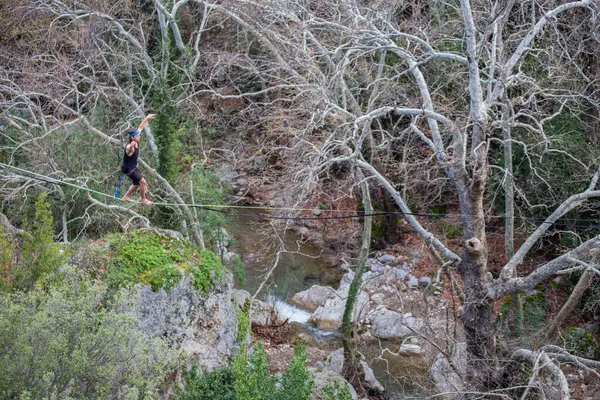 stock image A tightrope walker walks along a cable stretched over a canyon.