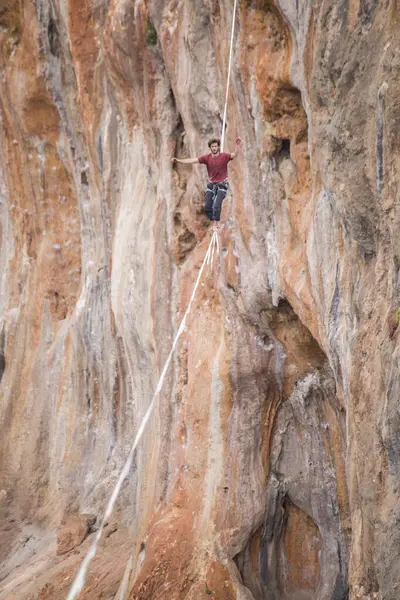 stock image A tightrope walker walks along a cable stretched over a canyon.