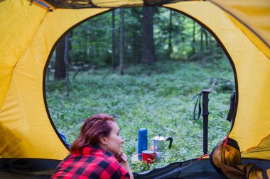 Ormanın ortasındaki bir açıklıkta kamp yapmak. Genç bir kız çadırda dinleniyor..