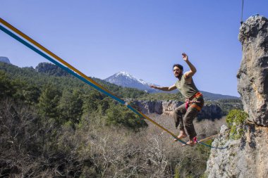 A tightrope walker walks along a cable stretched over a canyon. clipart