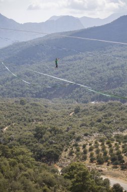 Bir ip cambazı, kanyonun üzerinde gerilmiş bir kablo boyunca yürür..