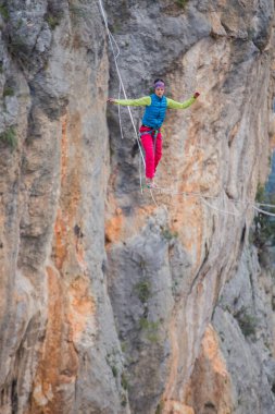 A tightrope walker walks along a cable stretched over a canyon. clipart