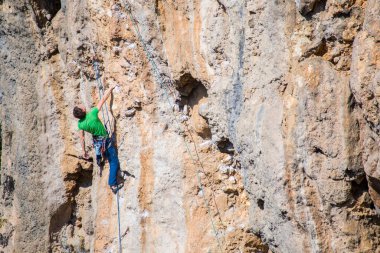Bir kaya tırmanıcısı zor bir yoldan zirveye tırmanır..