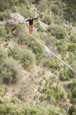 Bir ip cambazı, kanyonun üzerinde gerilmiş bir kablo boyunca yürür..