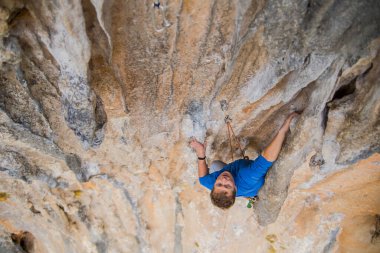Bir kaya tırmanıcısı zor bir yoldan zirveye tırmanır..