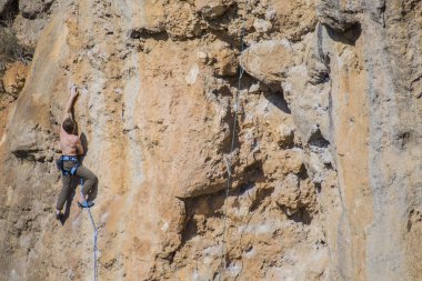 Bir kaya tırmanıcısı zor bir yoldan zirveye tırmanır..