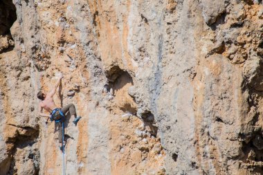 Bir kaya tırmanıcısı zor bir yoldan zirveye tırmanır..