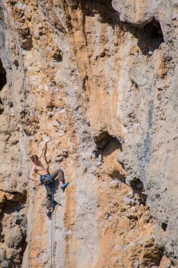 Bir kaya tırmanıcısı zor bir yoldan zirveye tırmanır..
