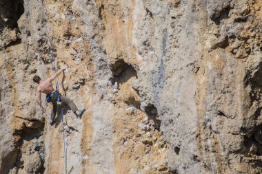 Bir kaya tırmanıcısı zor bir yoldan zirveye tırmanır..
