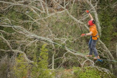 A tightrope walker walks along a cable stretched over a canyon. clipart