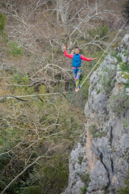 A tightrope walker walks along a cable stretched over a canyon. clipart