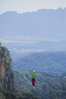 A tightrope walker walks along a cable stretched over a canyon. clipart