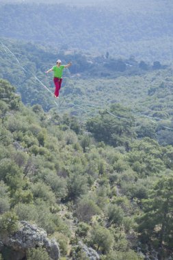 Bir ip cambazı, kanyonun üzerinde gerilmiş bir kablo boyunca yürür..