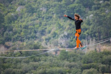 Bir ip cambazı, kanyonun üzerinde gerilmiş bir kablo boyunca yürür..