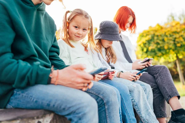 妹の女の子の子供たちが列に座ってスマートフォンのデバイスを閲覧している小さなかわいい女の子の肖像画 不注意な若い十代の時間と近代的な技術の概念イメージ — ストック写真